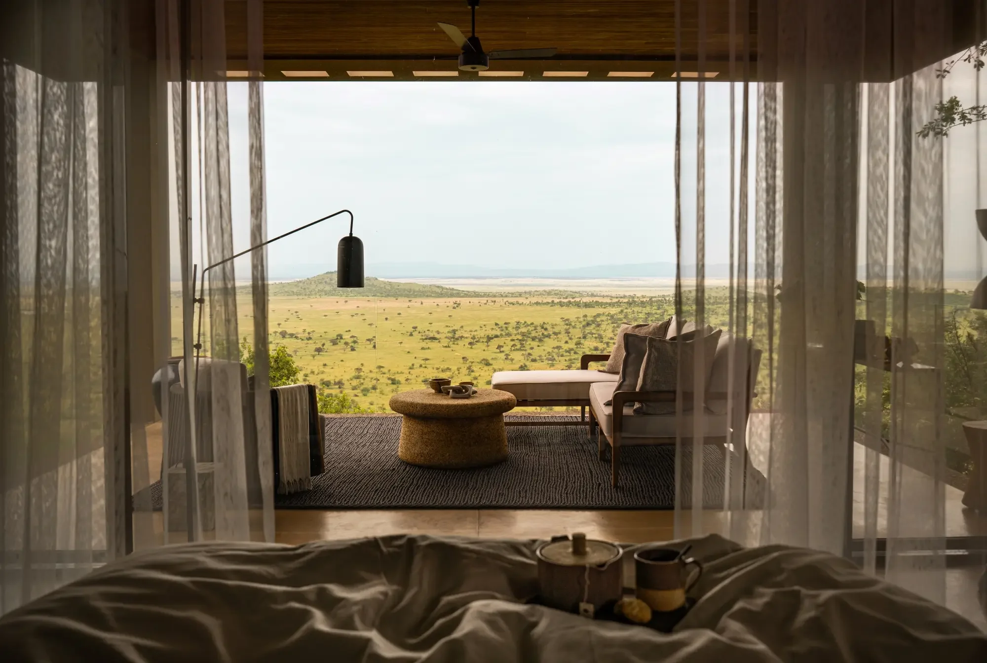 A bedroom looking through sheer curtains to the plains