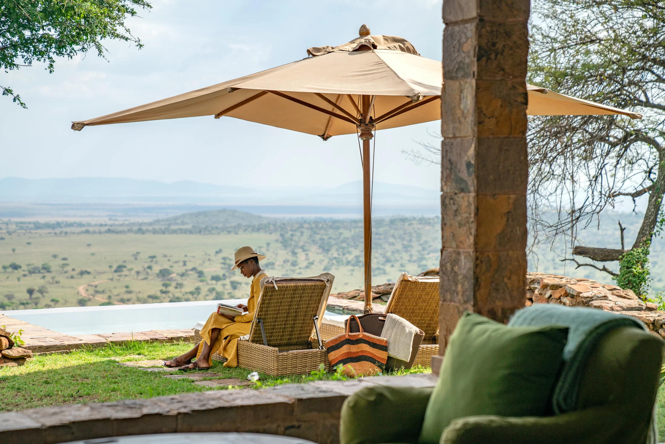 A guest beneath a parasol on the terrace above the plains