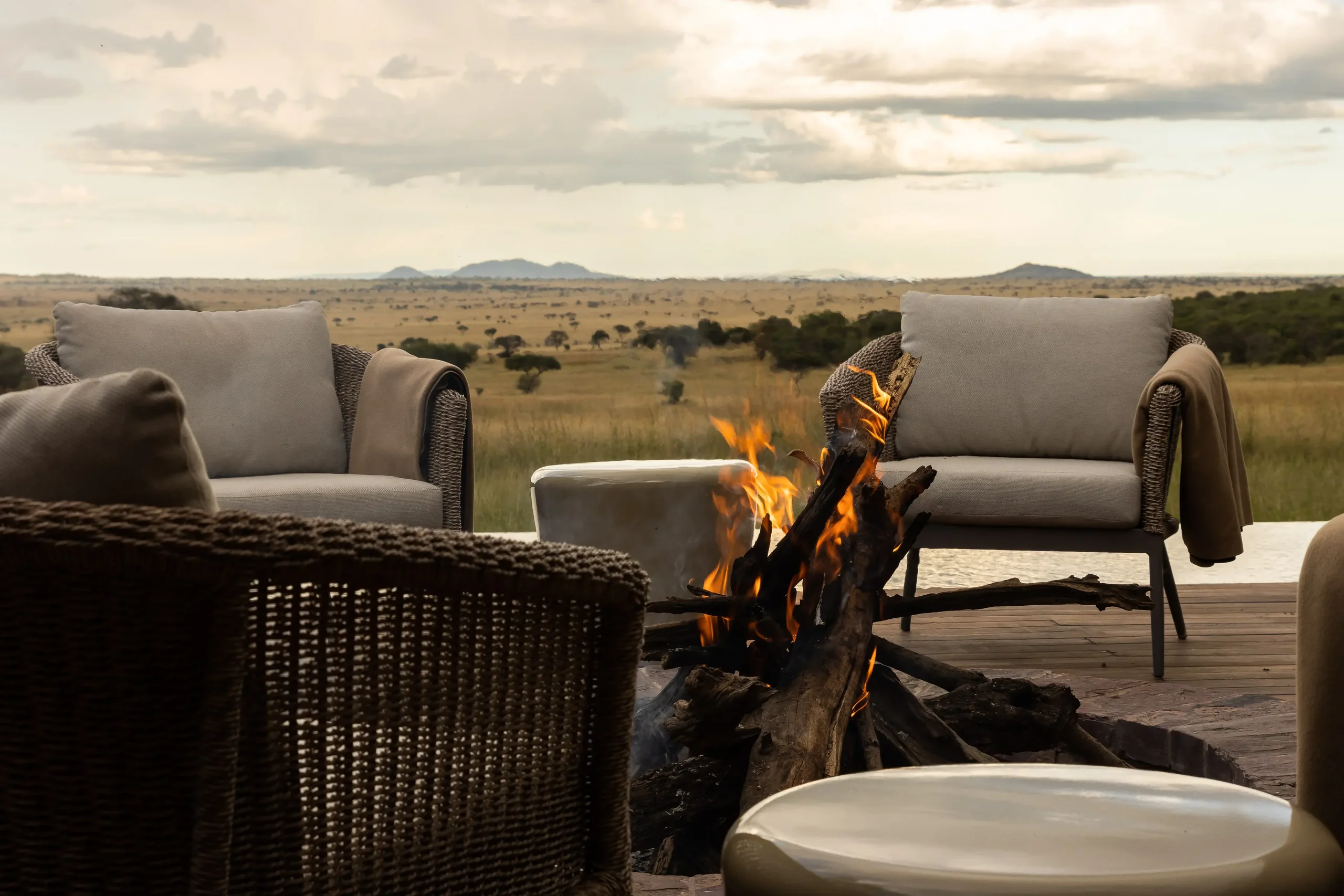 Armchairs around a fire on the deck at dusk