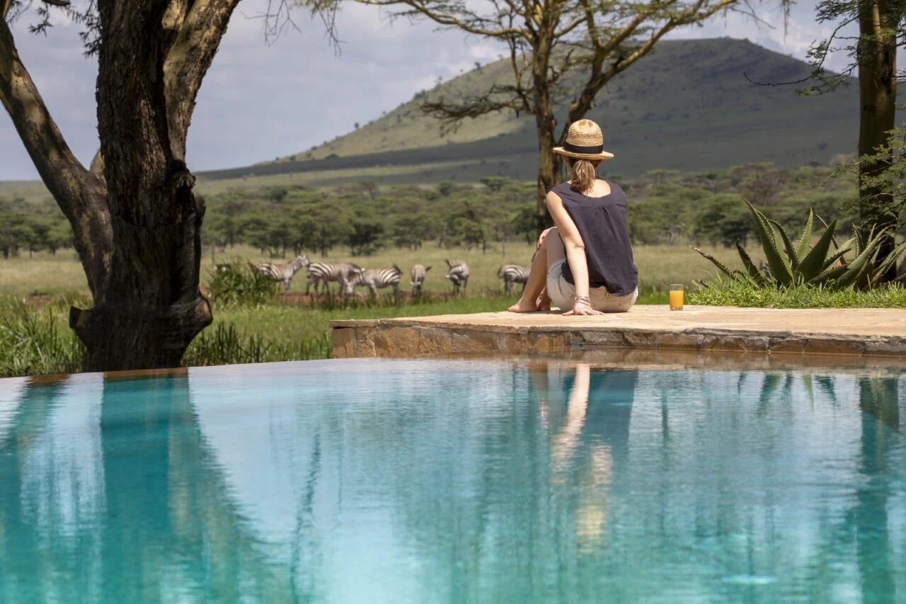 A guest by the infinity pool with a view of the plains