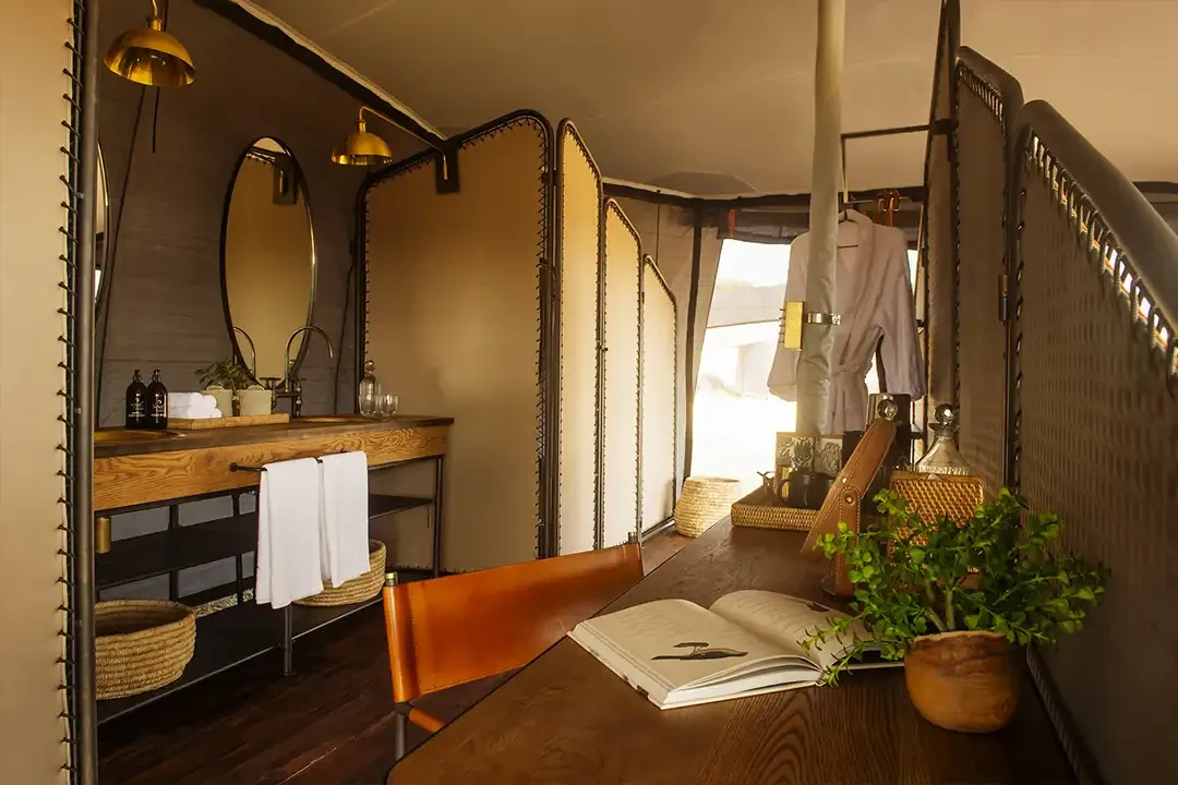 A tent bathroom with a basin, mirror and towels