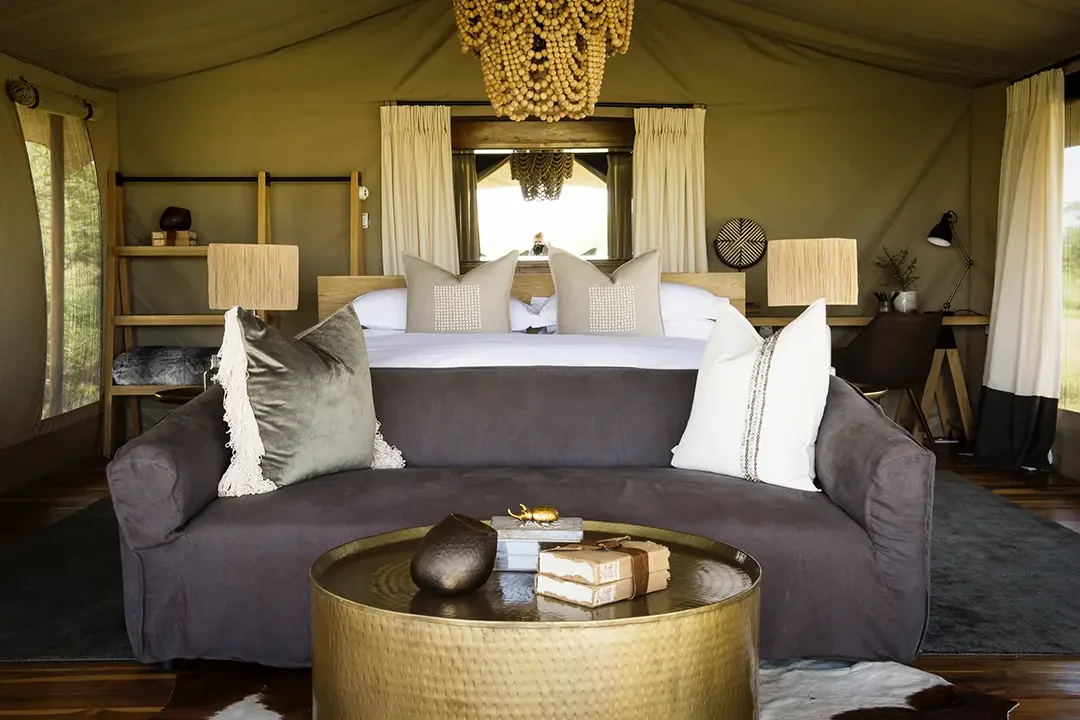 A tent bedroom with a velvet sofa and a brass table