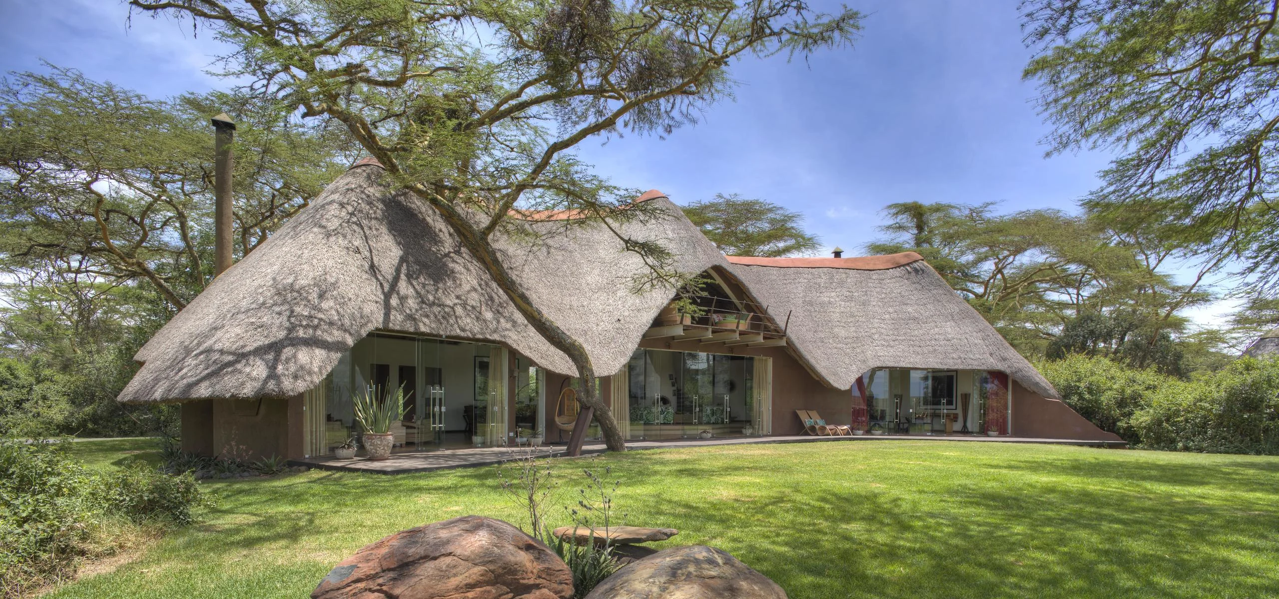 The thatched cottages on the lawn beneath the trees