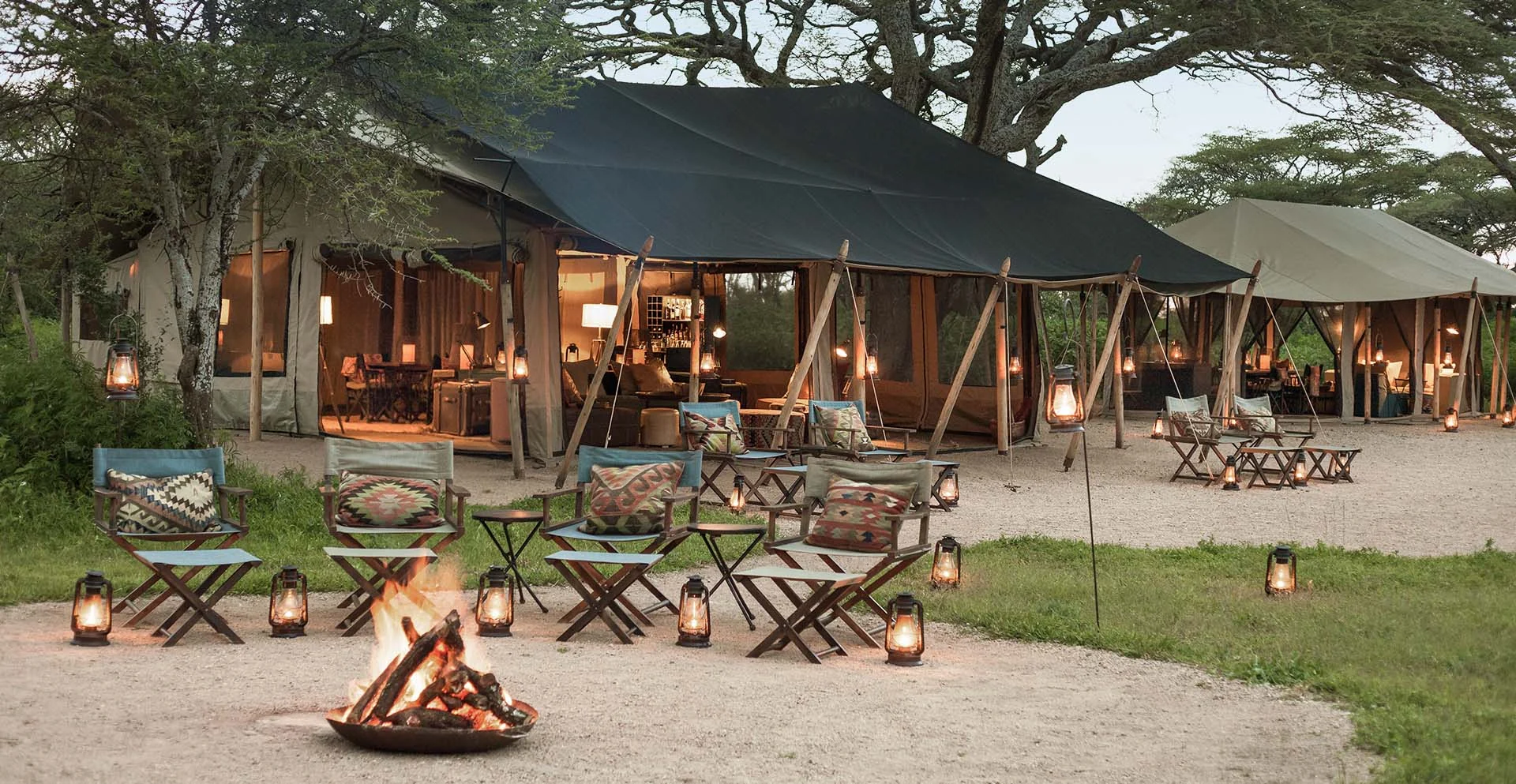 The main tent at dusk with a fire and lanterns