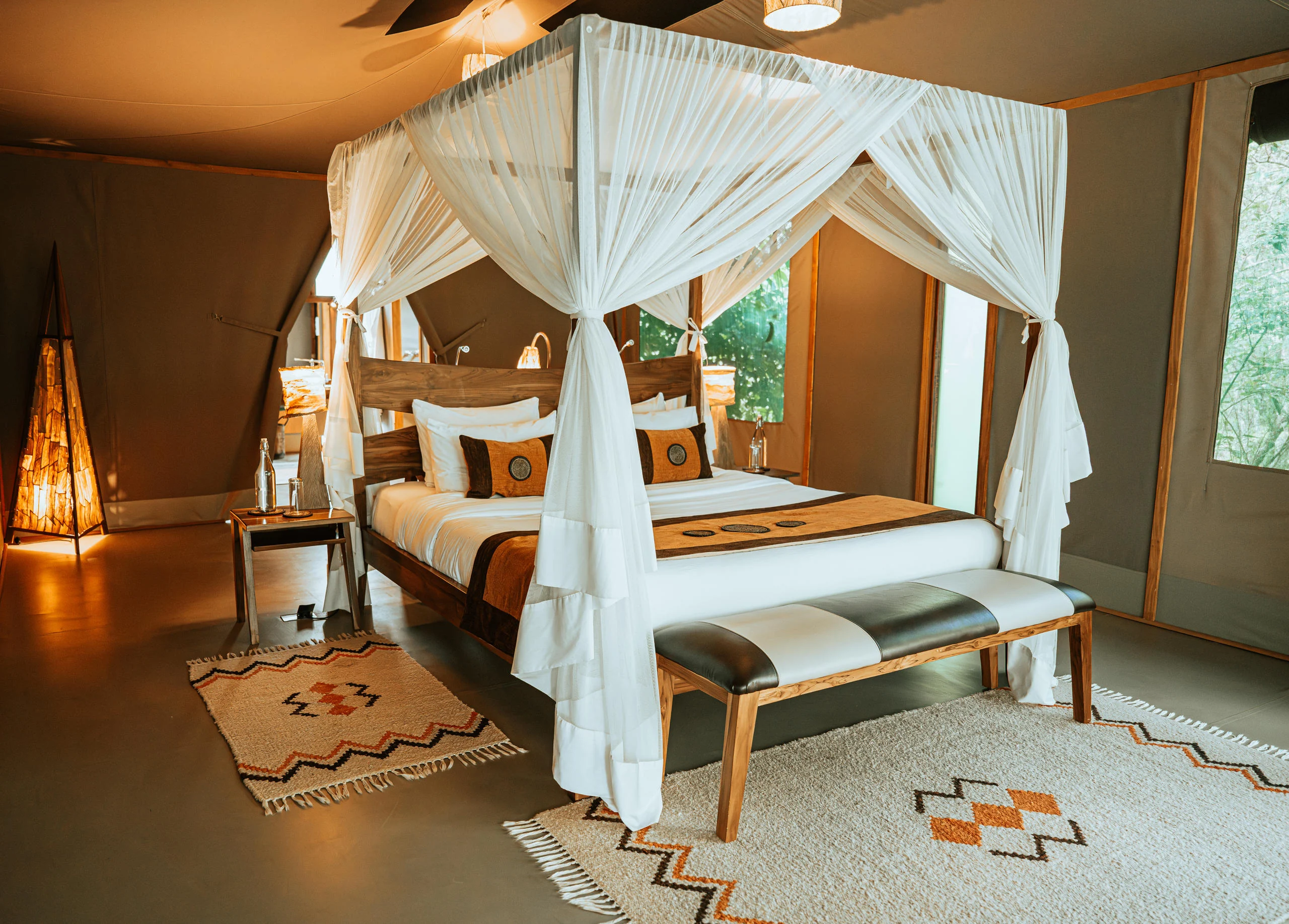 A tent bedroom with a draped bed and a patterned rug