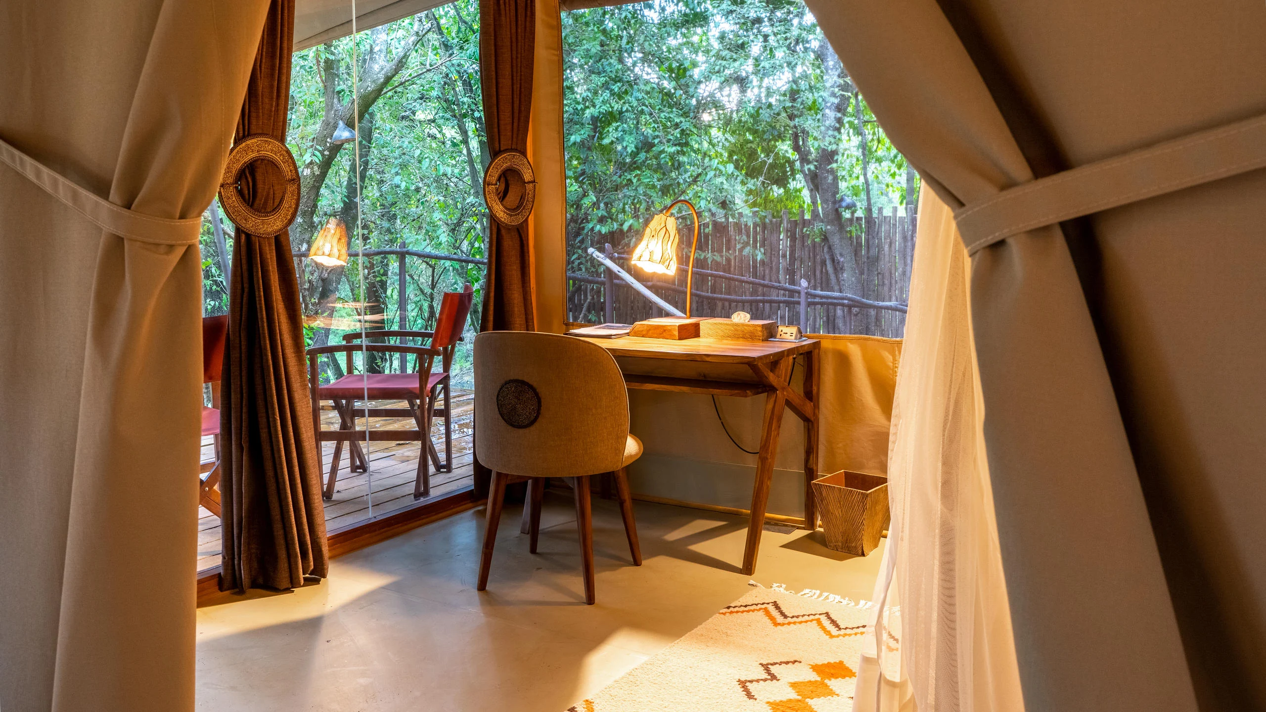 A tent with a desk and chair, open to the trees