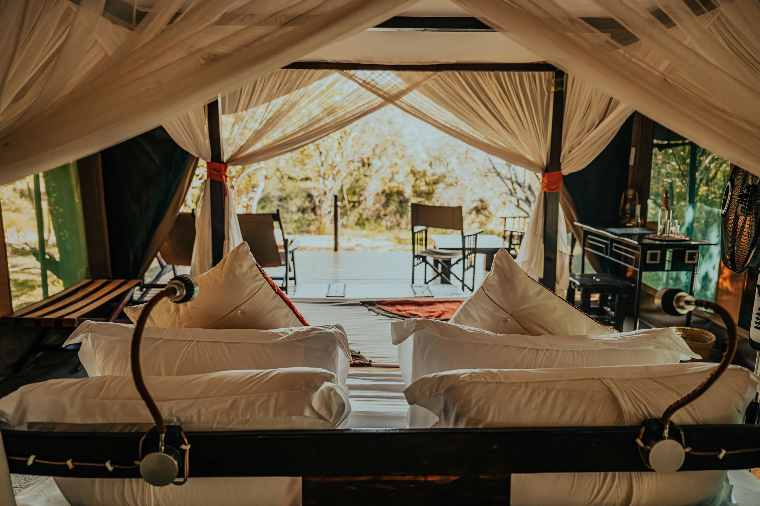 A tent bedroom with a draped bed, open to the trees