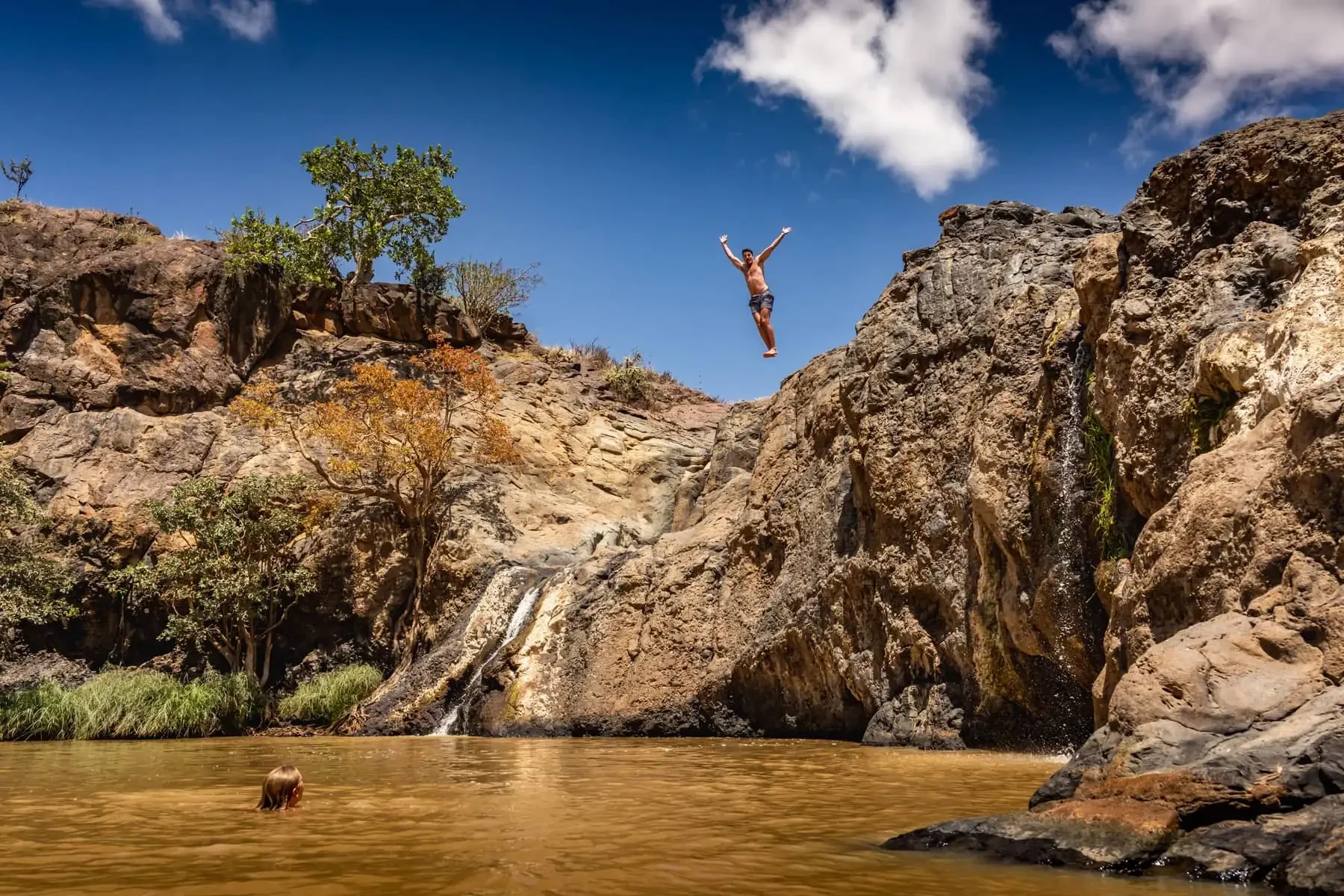 A guest leaping into the river pool between the rocks