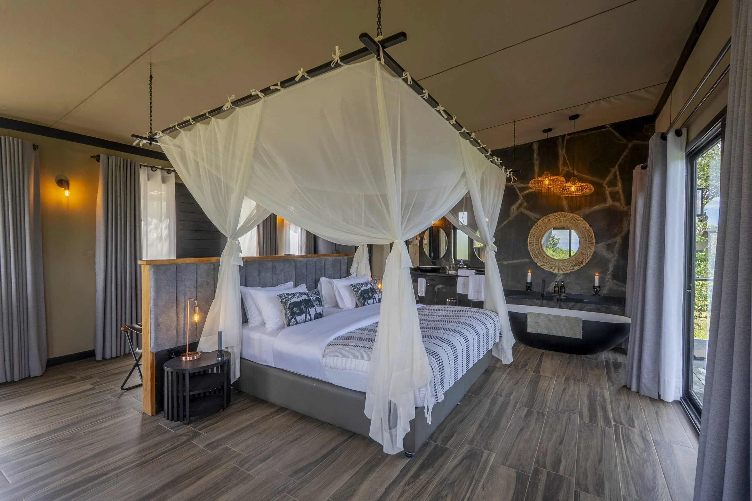 A bedroom with a draped four-poster bed and doors onto the balcony