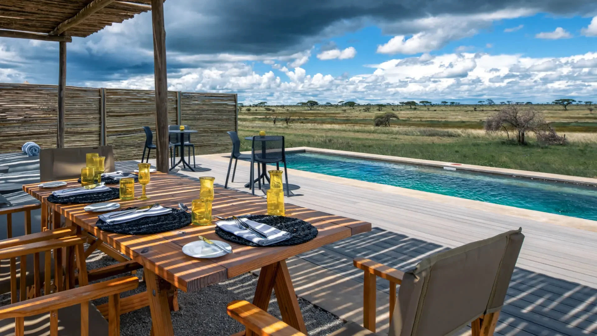 A dining table on the deck beside the pool, looking over the plains