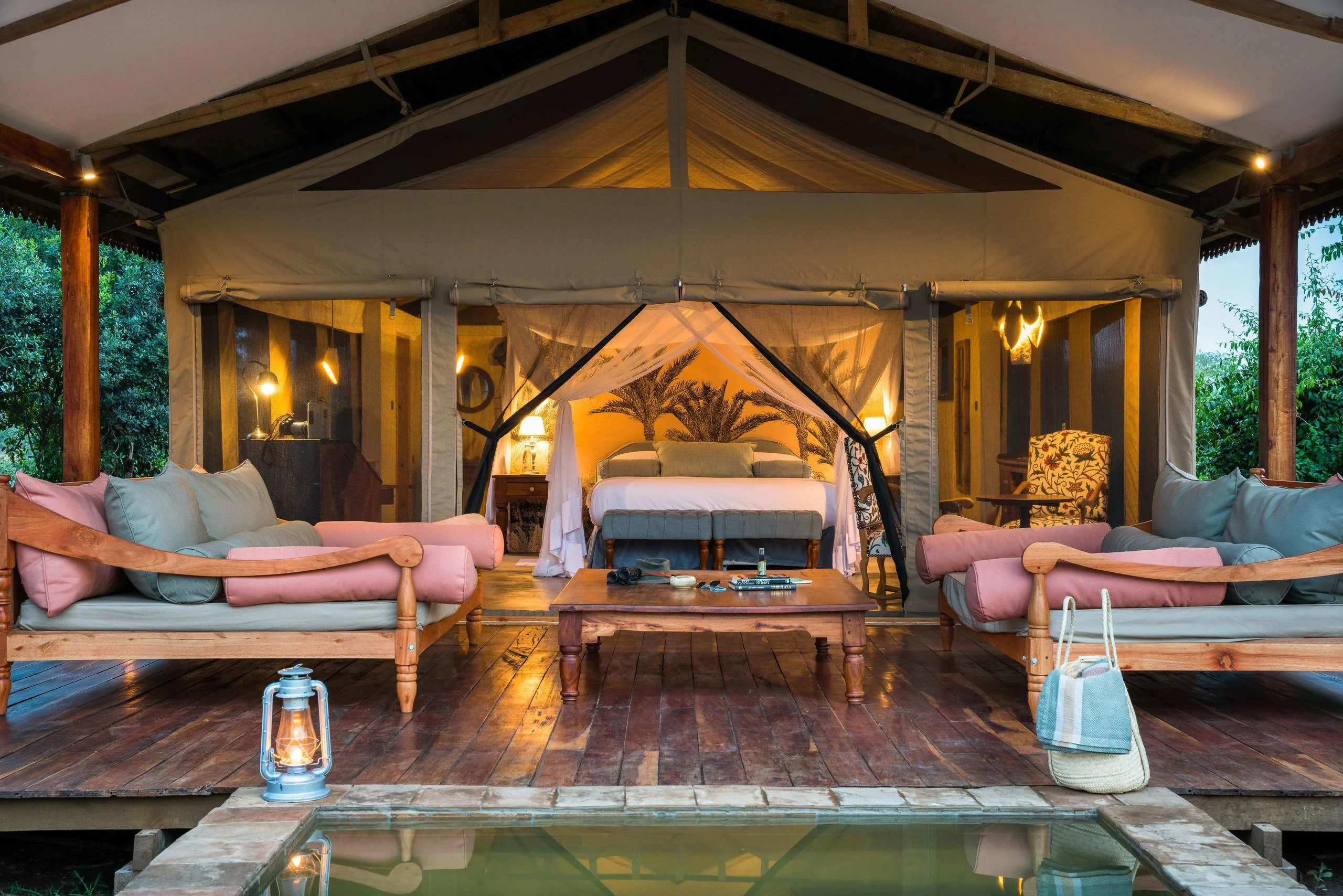 A tented suite with its sitting area and pool at dusk