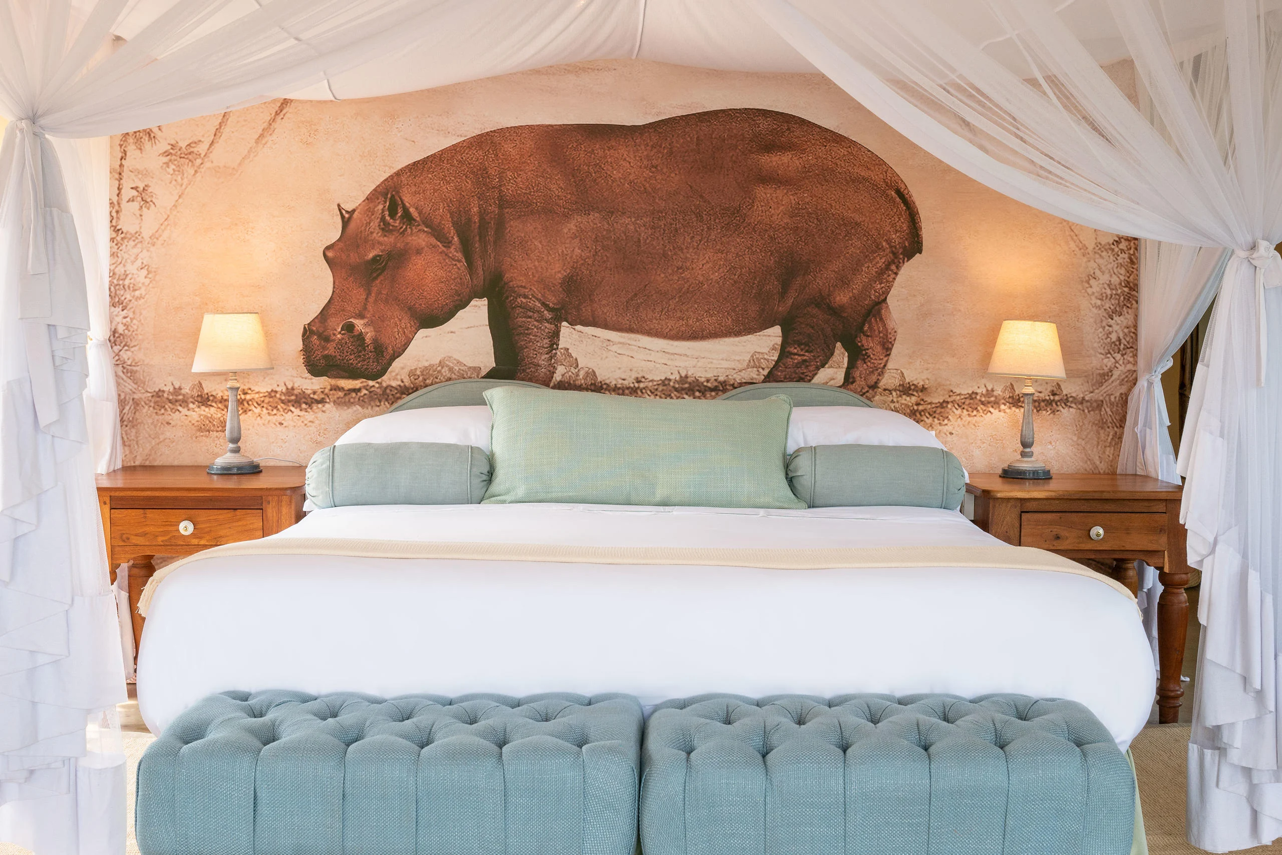 A bedroom with a painted hippo above the bed