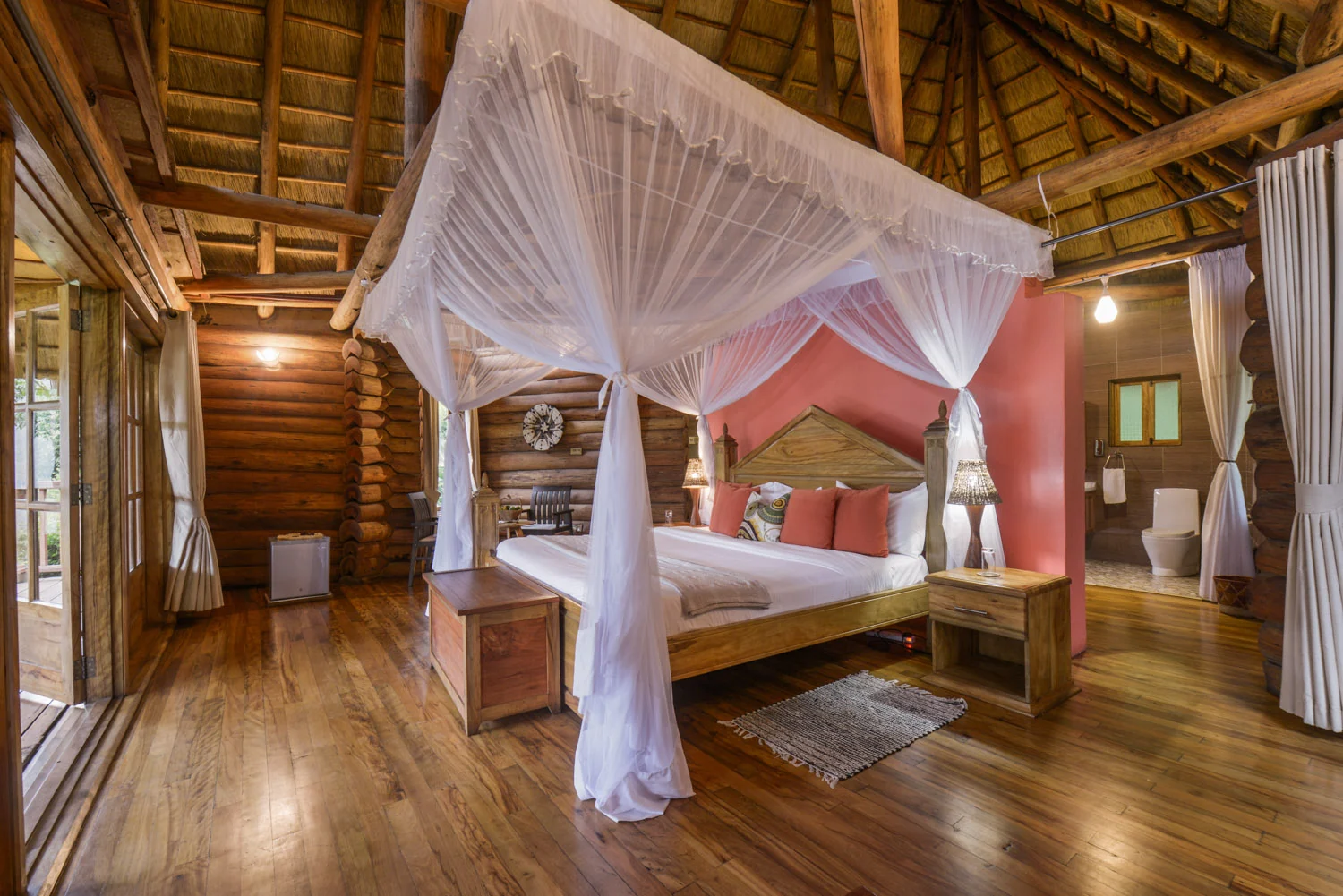 A cottage bedroom with a draped bed and timber walls