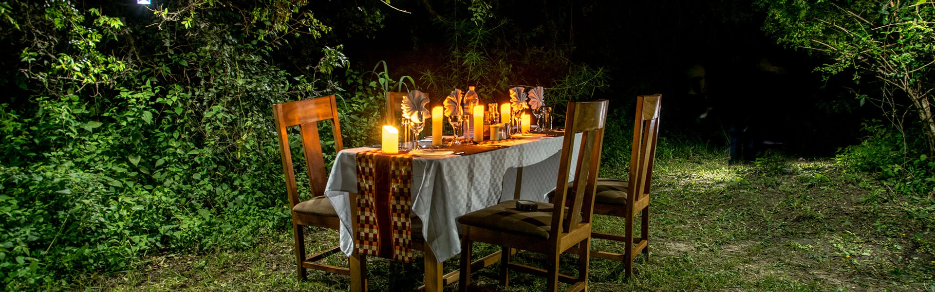 A table set for dinner in the bush, lit by candles