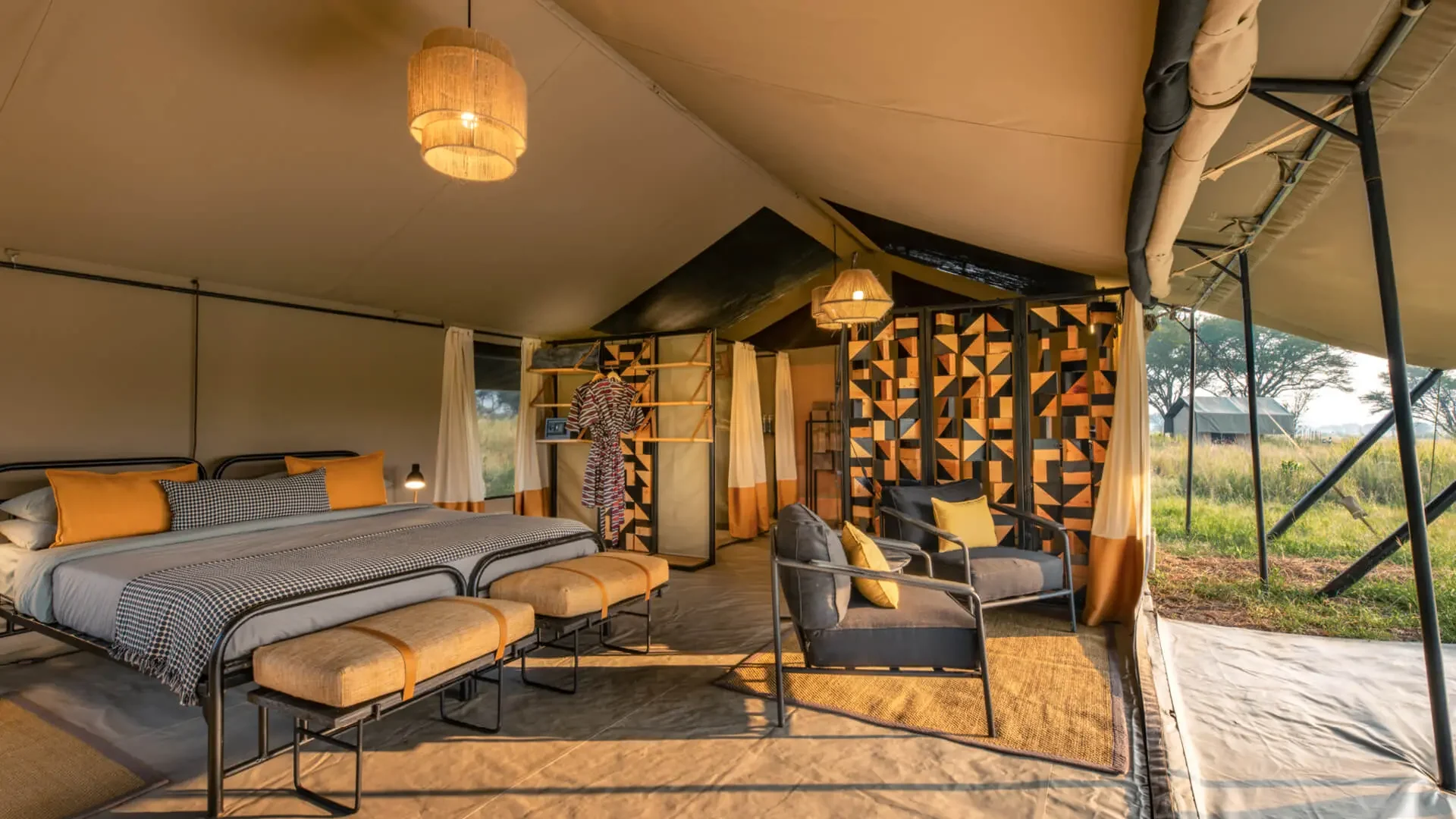A tent bedroom with a patterned screen and the plains beyond