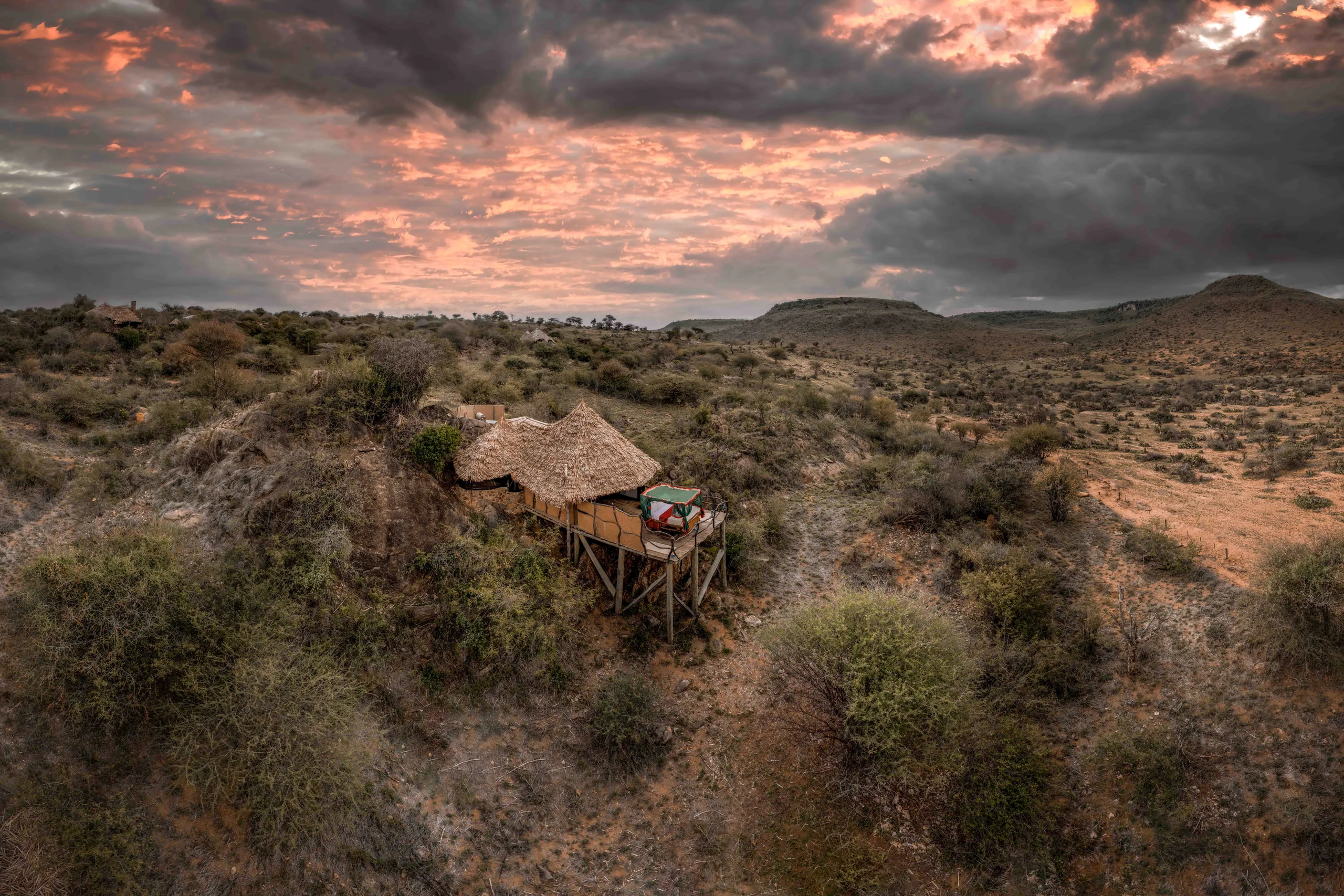 A raised sleeping deck among the rocks at Loisaba Star Beds at sunset